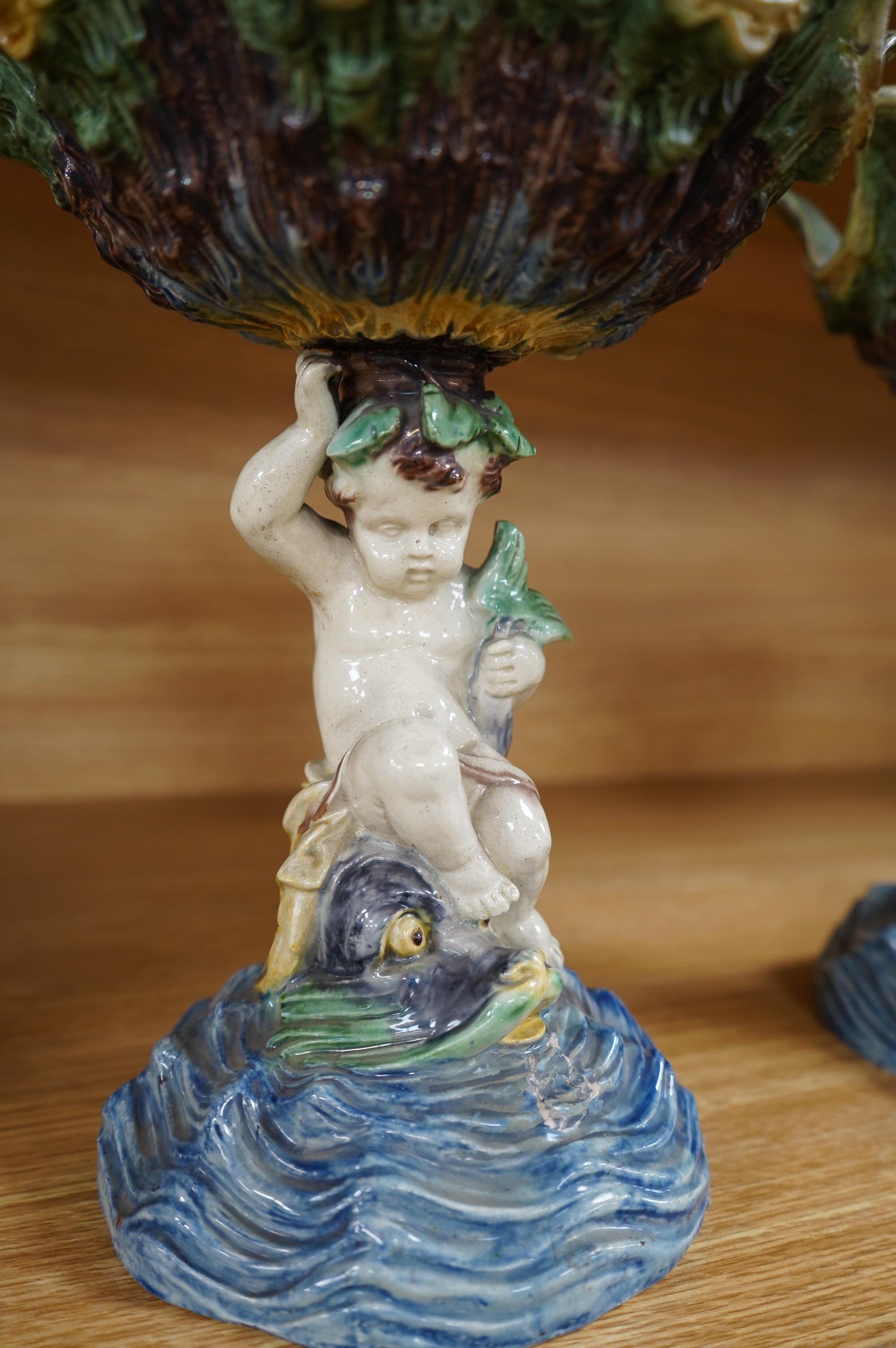 A pair of 19th century majolica comports with putti stems, 25cm. Condition - one repaired